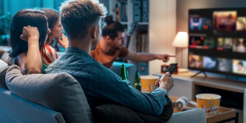 Friends choosing a movie to watch together at home, video on demand concept